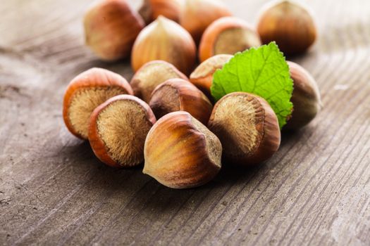 Hazelnuts with shell and green leaf on the wooden table