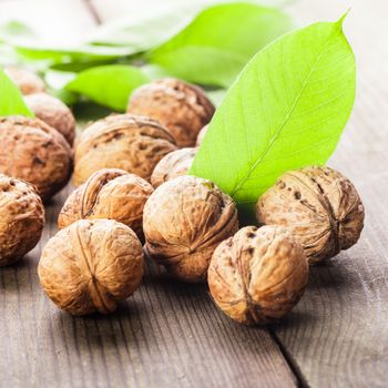 Walnuts with shell and green leaf on the wooden table