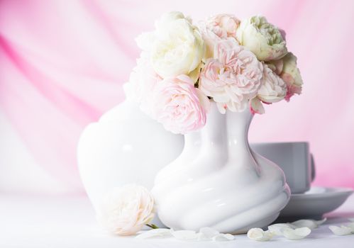 White and pink roses in a vase on pink background closeup