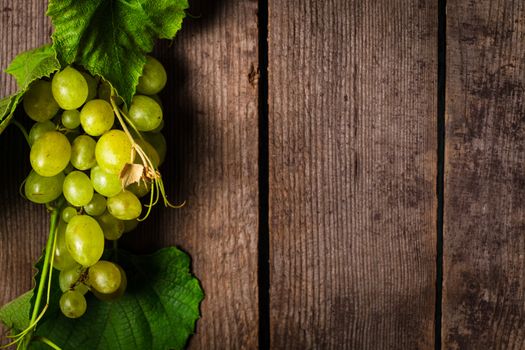 Grapes with leaves on the wood background closeup