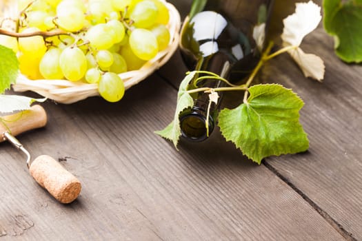 White wine, grapes, corkscrew, and cork on wood background closeup