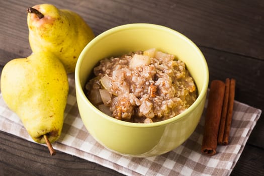 Oatmeal with pears and cinnamon and walnut on the wooden table