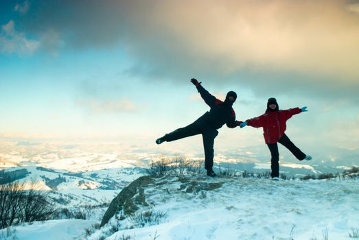 Landscape of two people at the peak of the mountain dancing in winter