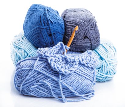 Crocheting with blue a balls of yarn on white