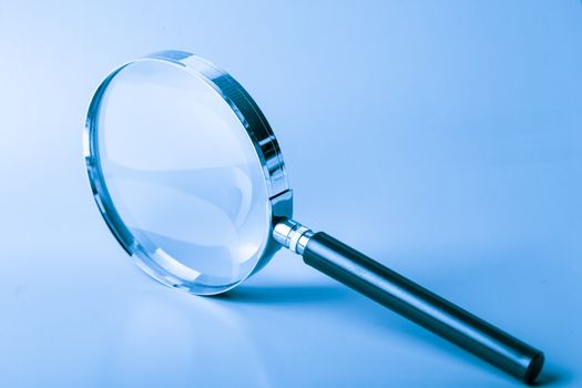 Magnifier on blue background close up