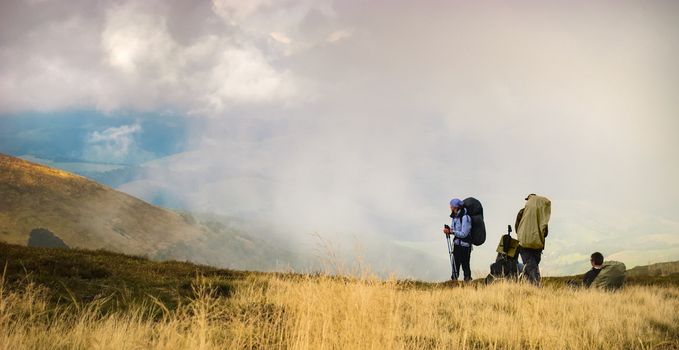 Three tourists in the mountains are resting after hiking