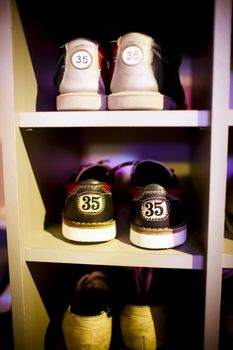 Old  bowling shoes placed in the cupboard, visible shoe sizes, fragment of wardrobe, vertical frame.