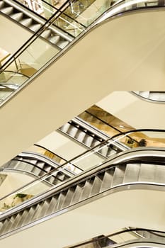 Modern escalators in the shopping centre, set in various plains, light fragments of elevation visible.
