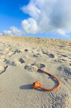 A fragment of the net rope on the beach, sky and white and grey clouds in the background.