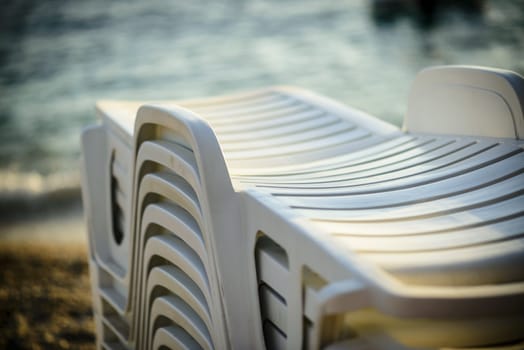 A few deckchairs ready for use on the beach, visible sea and beach, white sunbeds.