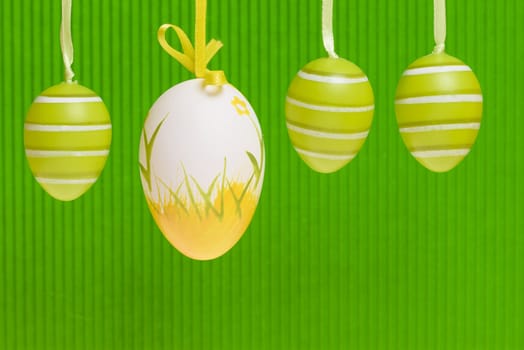 Easter decorated eggs on green backround, eggs in white and green and yellow colours.