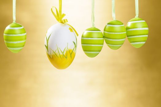 Easter decorated eggs on gold background, eggs in white and yellow and green colours, space for text  provided.