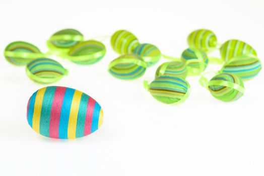 Photo presents Easter decorated striped eggs scatterded on white background.