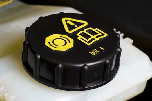 Vehicle maintenance fragment, Brake and clutch fluid check cap with black cap and yellow warning information.