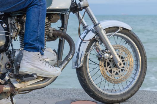 Someone on old motorcycle parking at the seaside in evening