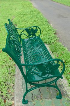 Green bench in park on grass near walkway