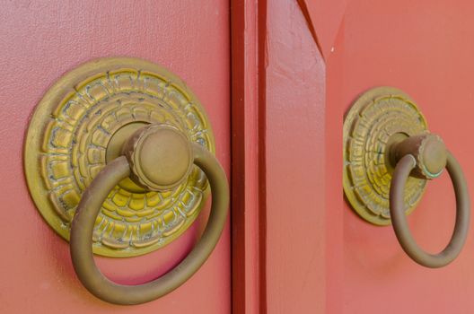Old golden knob installed on big red wood door
