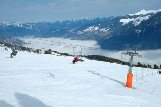 Ski lift, skiers and slope nearby Kaltenbach in Zillertal valley in Austria