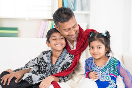 Happy Indian family at home. Living lifestyle of father and children in their traditional dress in modern house.