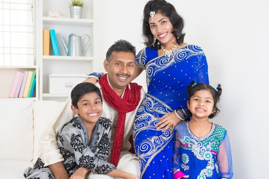 Portrait of happy Indian family at home. Living lifestyle of parents and children in their traditional dress in modern house.