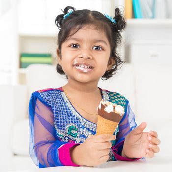 Eating ice cream. Cute Indian Asian girl enjoying an ice cream. Beautiful child model at home.
