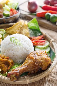 Popular delicious Indonesian local food nasi ayam penyet, indonesian fried chicken rice with sambal belacan. Fresh hot with steam smoke.