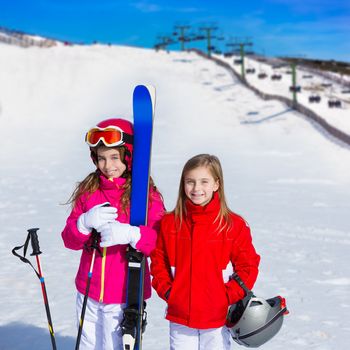 Kid girls sister in winter snow with ski equipment helmet goggles poles