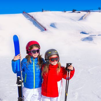 Kid girls sister in winter snow with ski equipment helmet goggles poles