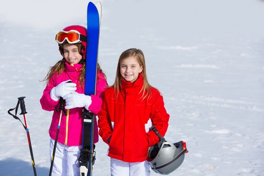 Kid girls sister in winter snow with ski equipment helmet goggles poles