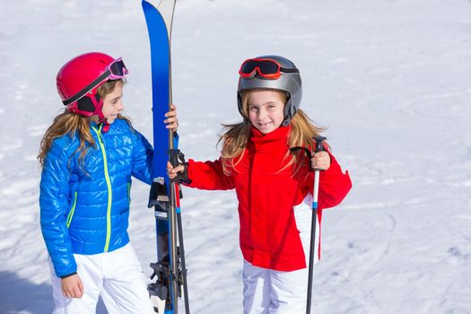 Kid girls sister in winter snow with ski equipment helmet goggles poles