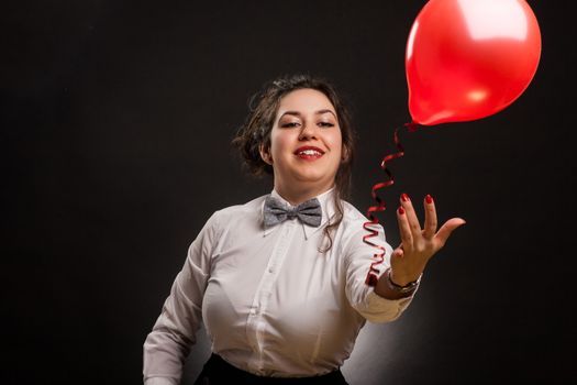 happy stylish woman playing with red balloon