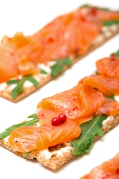 Salted salmon on crispy bread with cheese and arugula, closeup