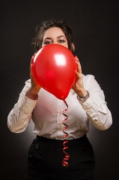 happy stylish woman playing with red balloon