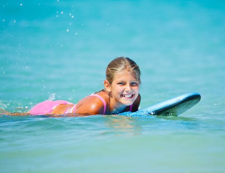Summer vacation - Happy cute girl having fun with surfboard in the ocean
