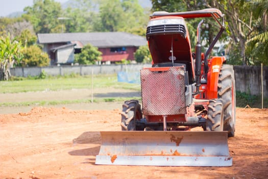 orange tractor is on the brown and dusty land