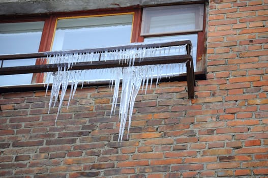 Big icicles at a window, against a brick wall