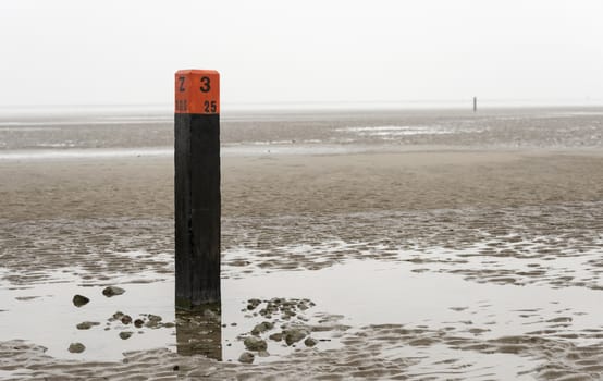 beach pole on wet sand and mud at low waterlevel