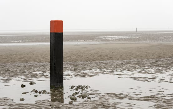 beach pole on wet sand and mud at low waterlevel