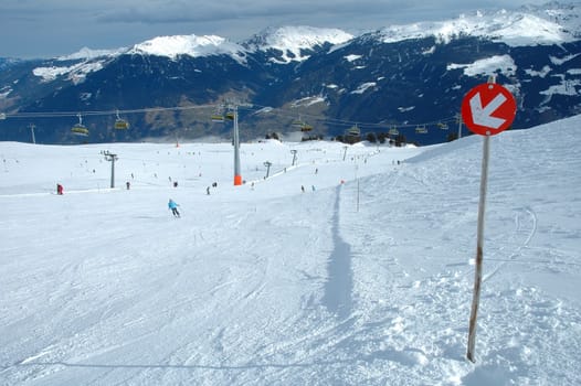 Slope direction sign and skiers on slope in Austria nearby Kaltenbach in Zillertal valley