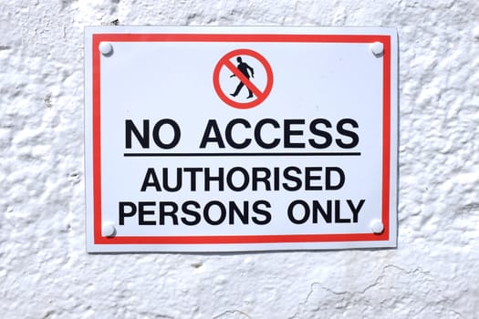 A sign with a white background and red rectangle with the words 'NO ACCESS AUTHORISED PERSONS ONLY' written in black and the symbol for no access above.