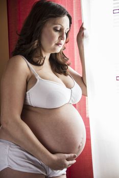 pregnant woman with white pants and white vest that looks out the window