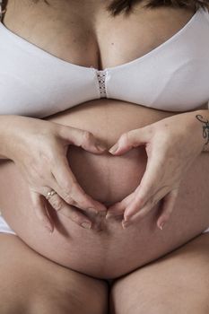 Close-up of a young pregnant female lying on a bed in her apartment