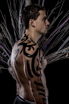 Tradition. Young attractive retro model in old-fashioned wild clothing Tribe. Tattoo. Native savage man