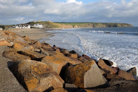 A view of Aberdaron beach Lleyn peninsular, Wales, UK. From rocks across the sea and sand to the village in the distance.