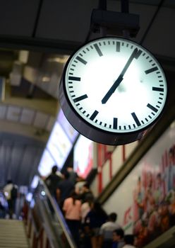 Public clock in railway station, people background 