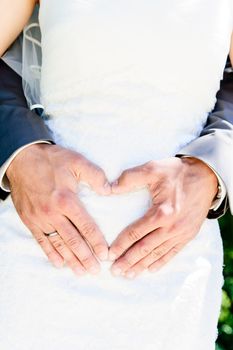 Heart shape made with hands of a wedding couple