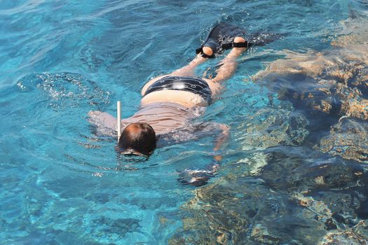 Woman photographer diving into water of Red sea