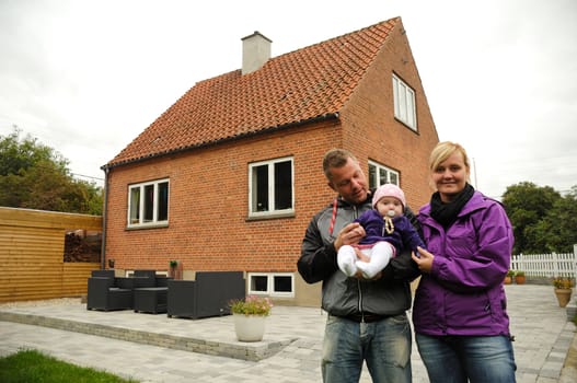 Happy family is standing in front of a house.