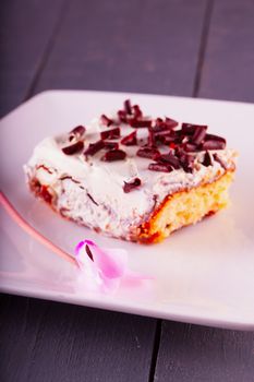 Cake slice with cyclamen over white plate, focus on flower