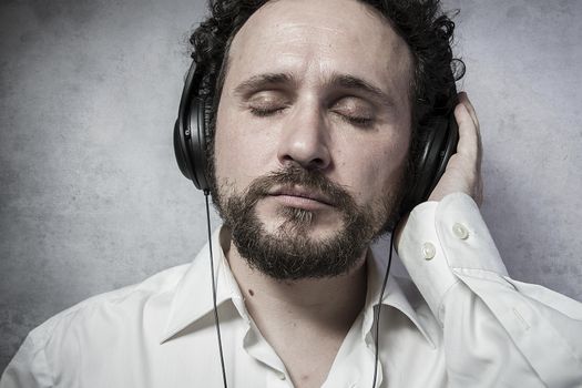Trendy, listening and enjoying music with headphones, man in white shirt with funny expressions